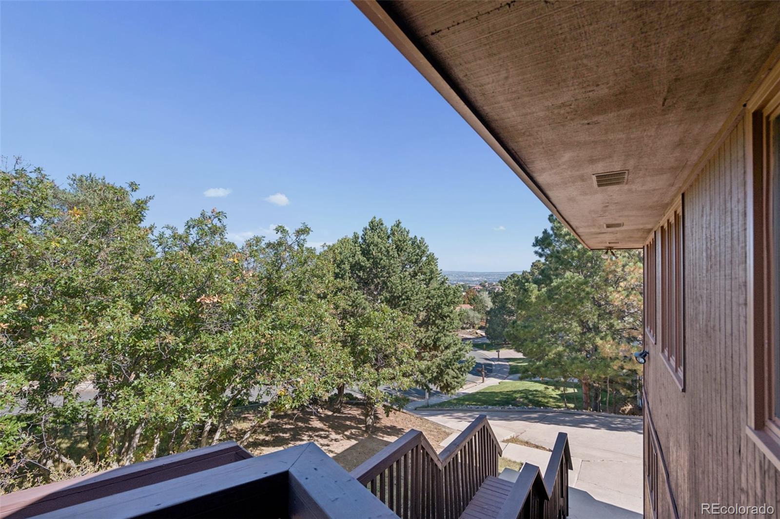 Covered deck stairs overlook mature trees, nearby homes, and streets.