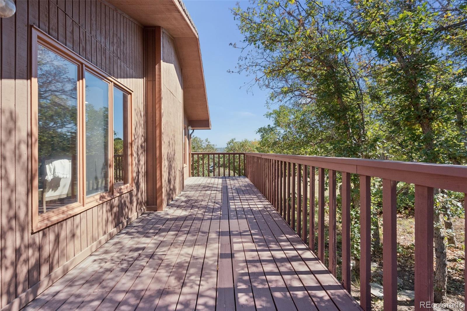 Wooden deck beside the home, with a railing overlooking leafy trees.
