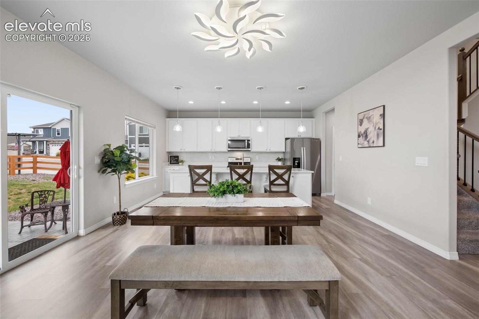 Open-plan kitchen and dining area with white cabinetry, stainless appliances, and a patio door.