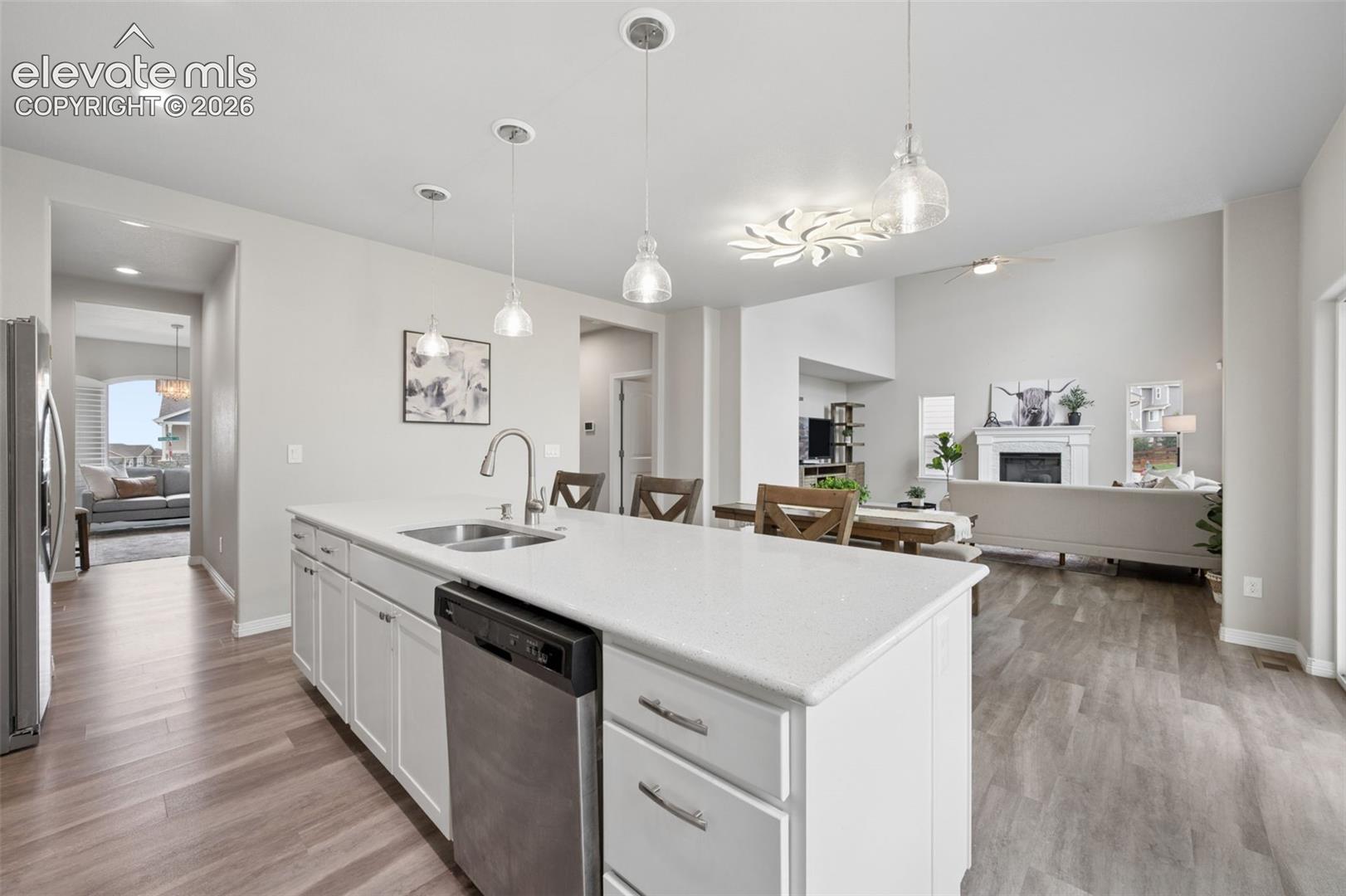 Open-plan kitchen with a large white island, pendant lights, and adjoining dining and living areas.
