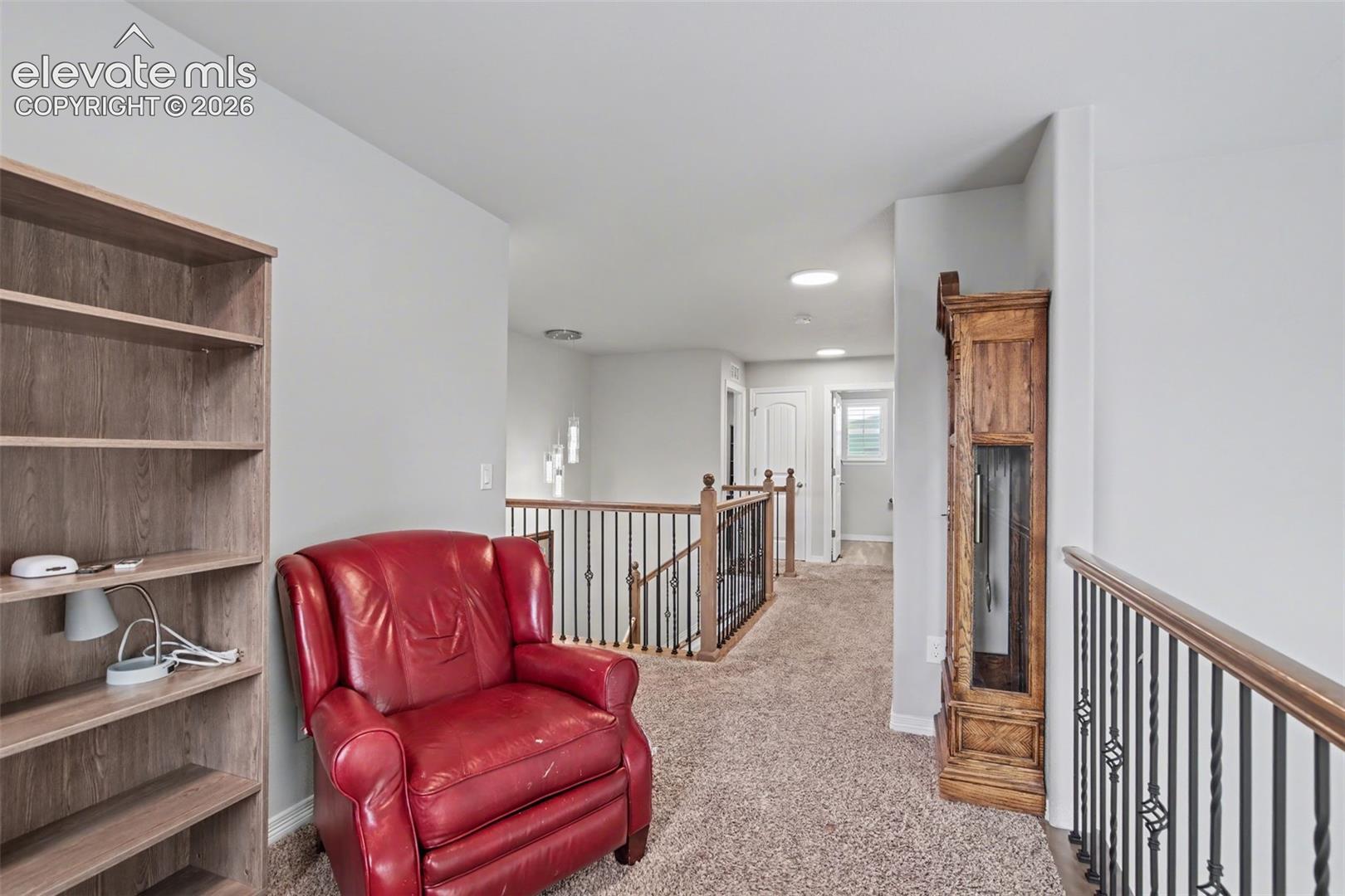Carpeted upstairs landing with a red leather armchair, built-in shelves, and wood-and-metal railings.