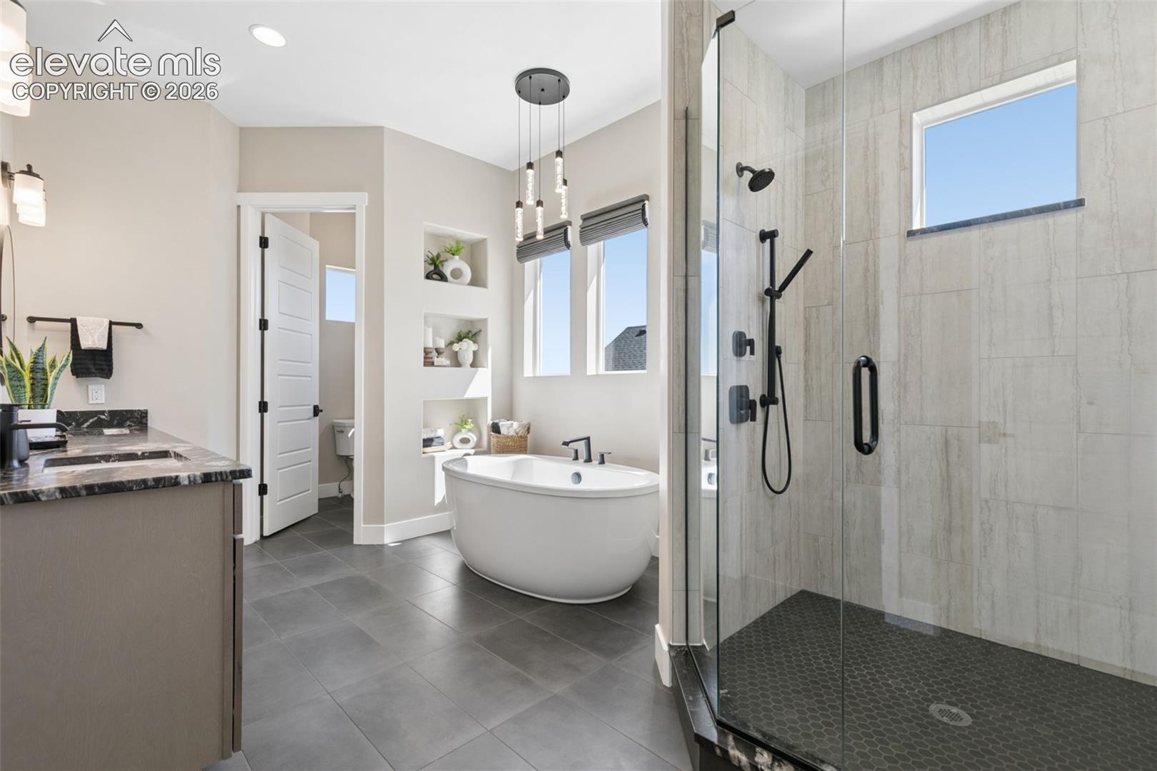Contemporary bathroom with a freestanding soaking tub and glass-enclosed marble-look shower.