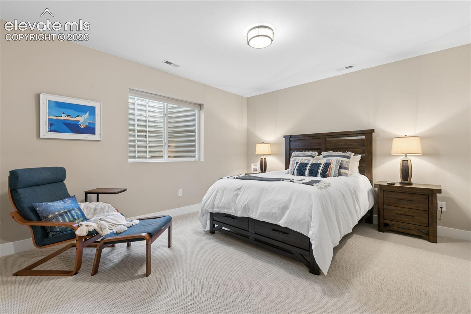 Bedroom with a dark wood bed, white bedding, matching nightstands, and a blue lounge chair.