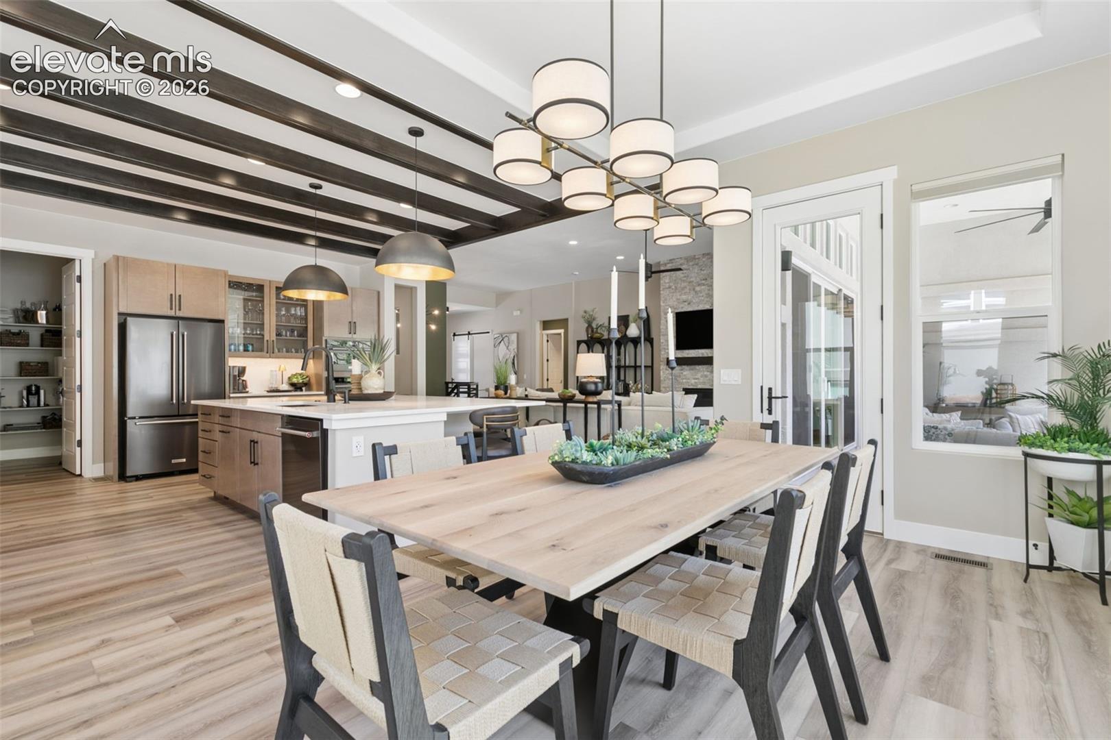Open-concept kitchen and dining area with dark ceiling beams and a long wood dining table.