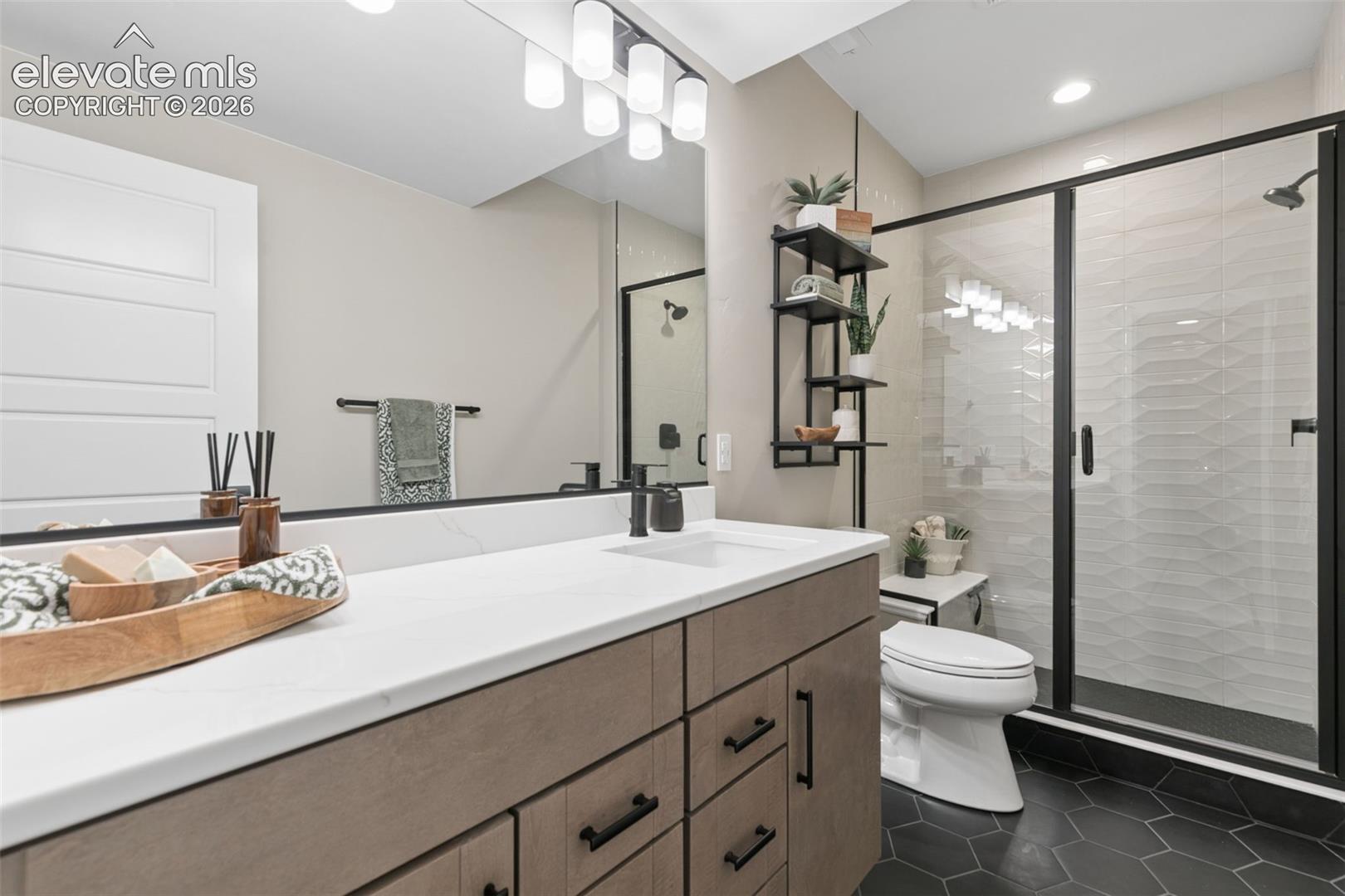 Modern bathroom with a long wood vanity and black-framed glass shower.