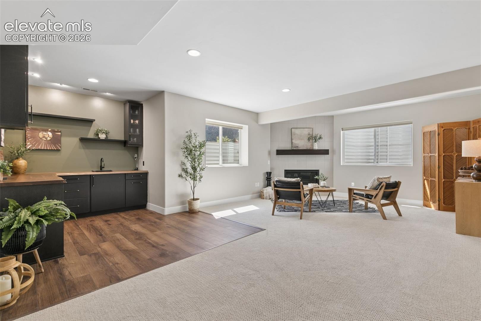 Open-plan living room and kitchen with dark cabinets, fireplace, and wood-look flooring.