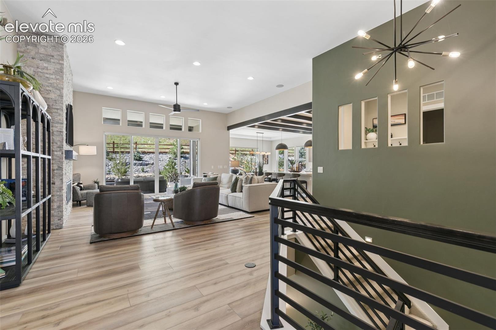 Open-plan living room with a stone fireplace, large windows, and a dining area beyond.
