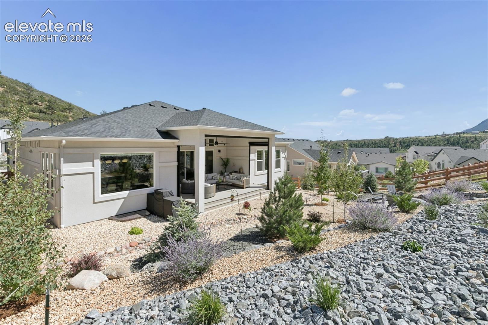 Modern home with a covered patio, outdoor seating, and a rock-and-gravel landscape.