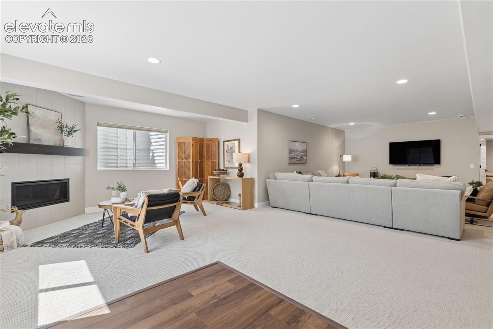 Furnished living room with a gray sectional, wall-mounted TV, and built-in fireplace.