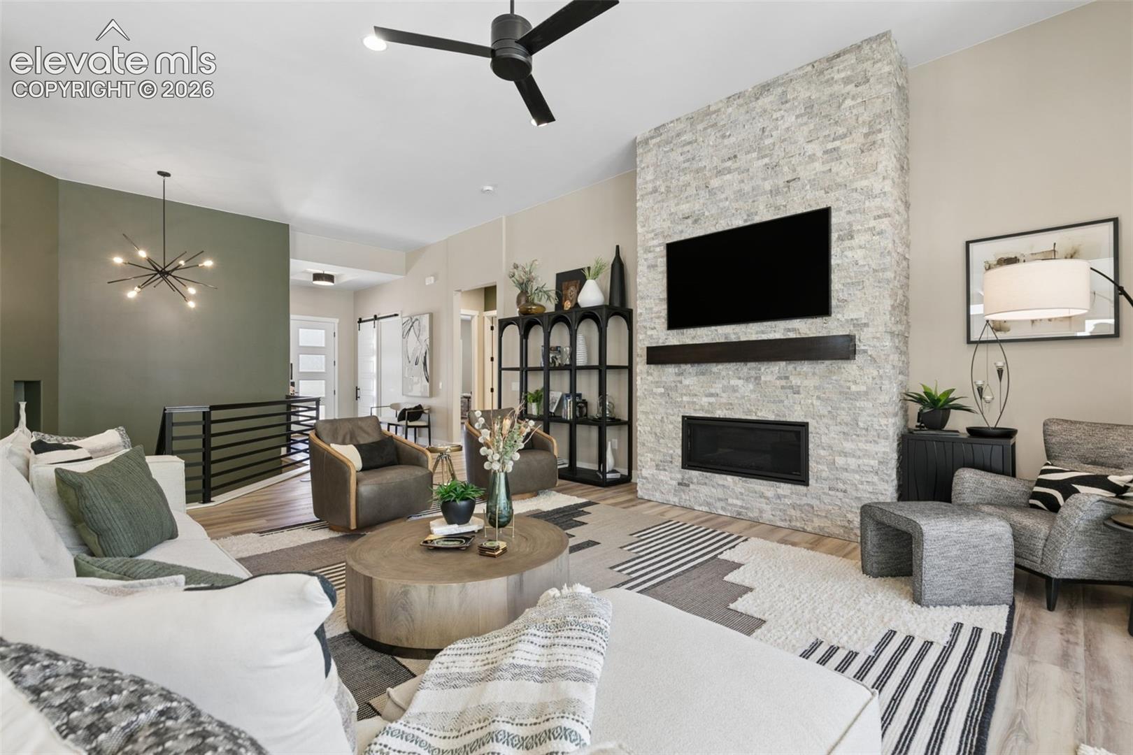 Living room with a tall stone fireplace wall, mounted television, and contemporary seating.