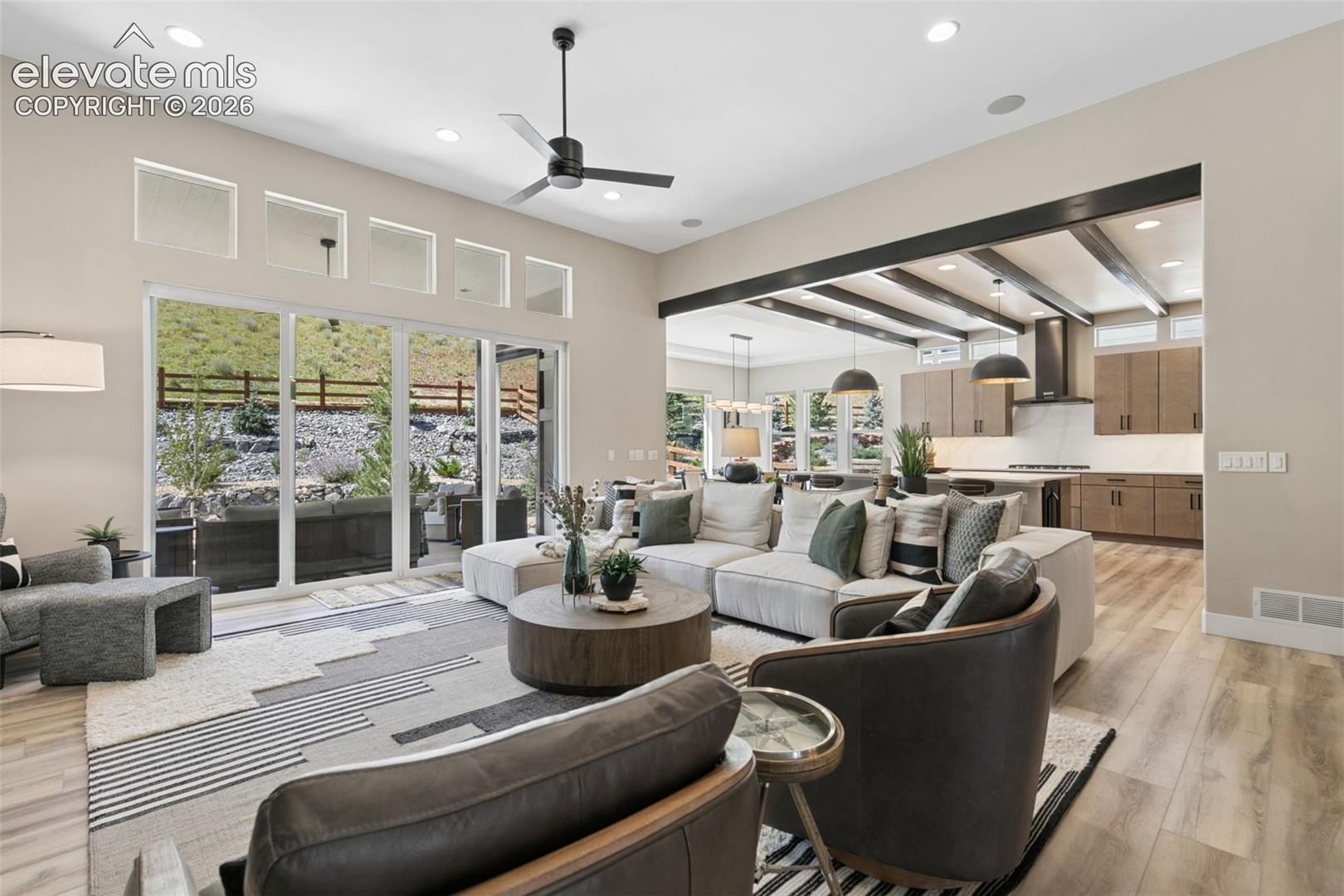 Open-plan living room and kitchen with exposed beams and sliding glass doors to a patio.
