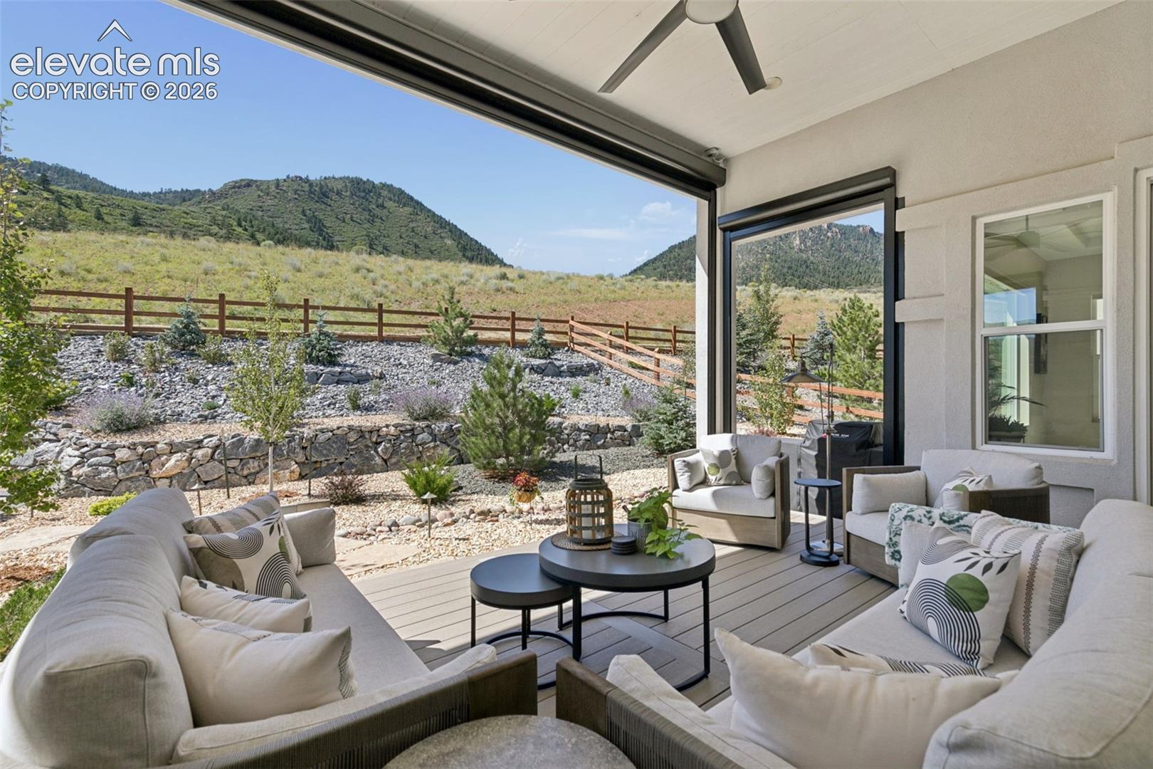 Covered patio with outdoor seating and a wide view of landscaped grounds and wooded hills.