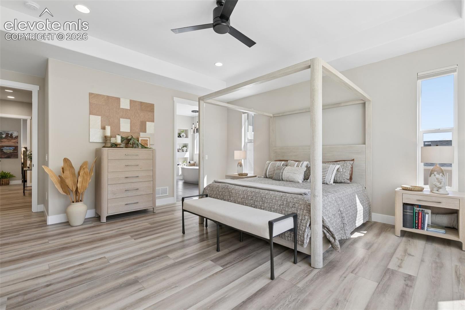 Staged bedroom with a pale wood four-poster bed and upholstered bench.