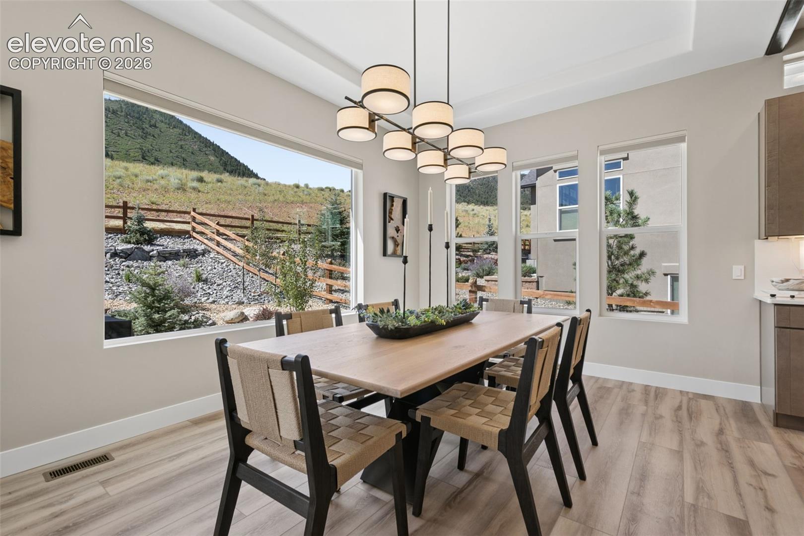 Dining room with a long wood table and large windows overlooking a mountain slope.