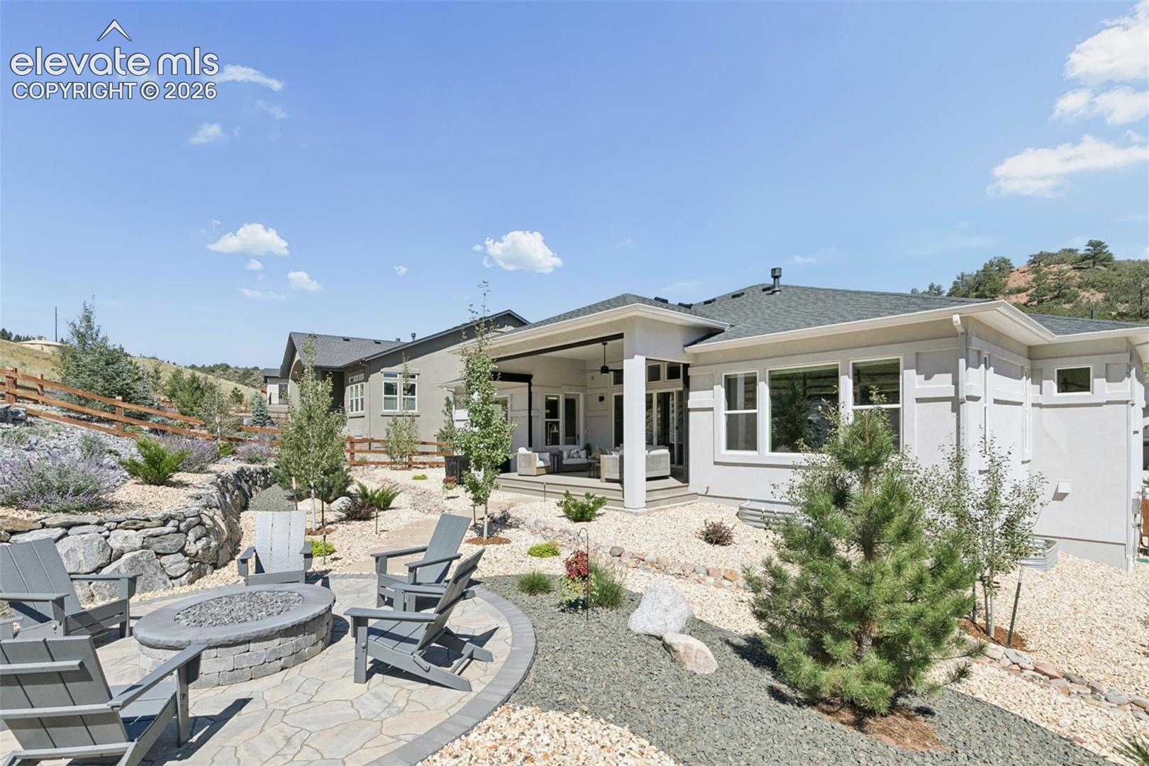 Modern home's rear exterior with covered patio and stone fire pit seating.