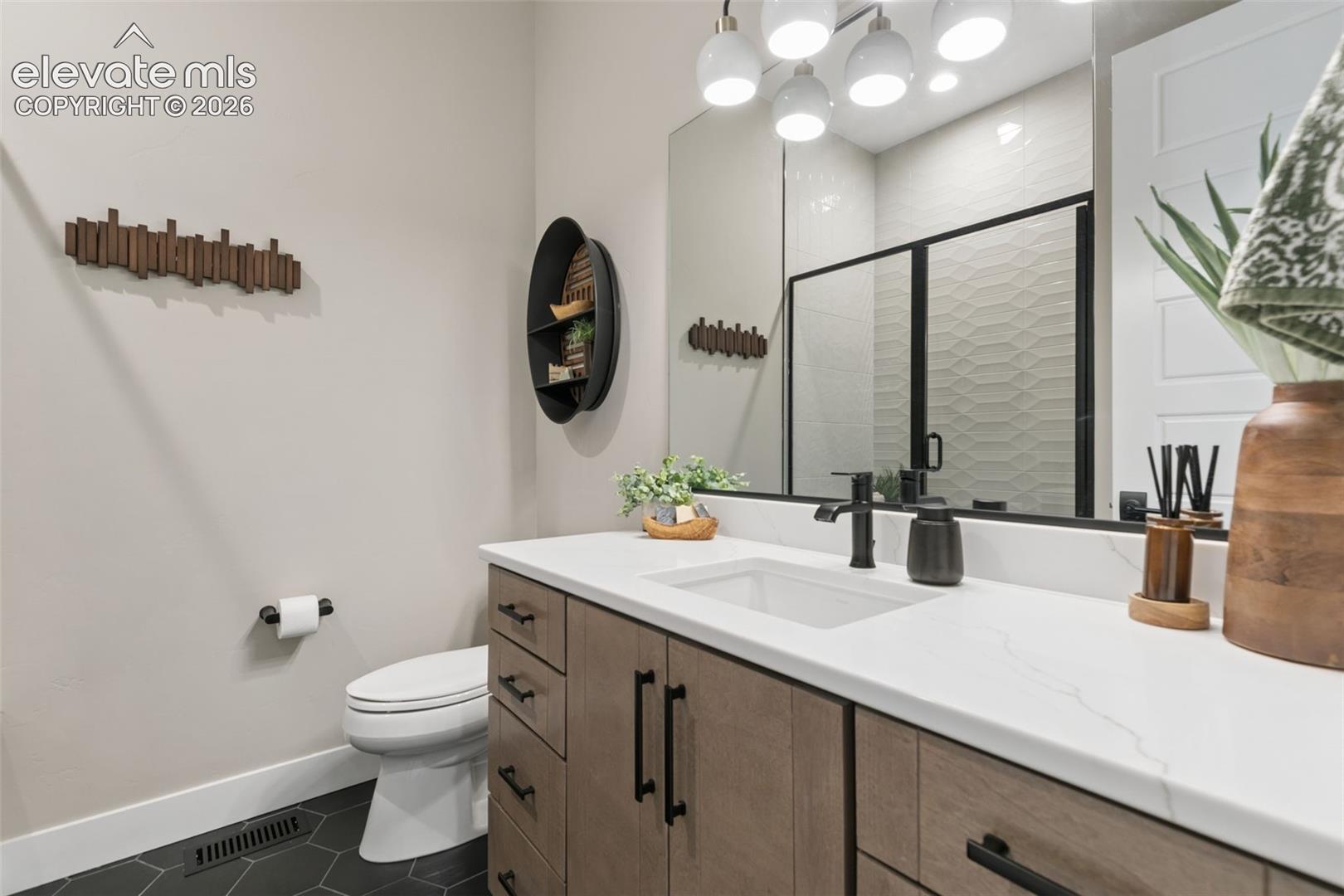 Bathroom with a wood vanity, black fixtures, large mirror, and glass-enclosed tiled shower.
