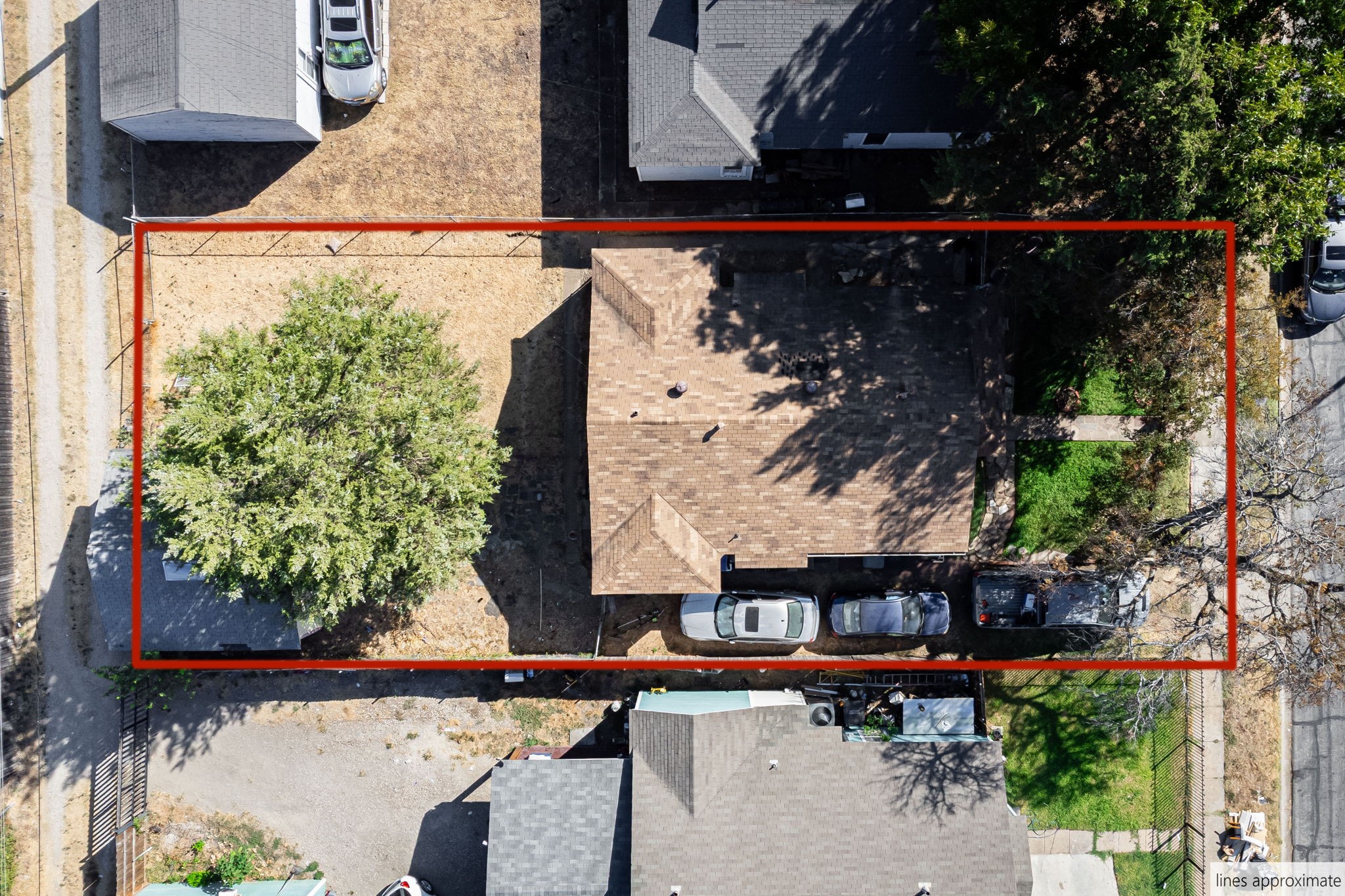 Aerial view of a house and lot outlined in red, with neighboring homes and trees.