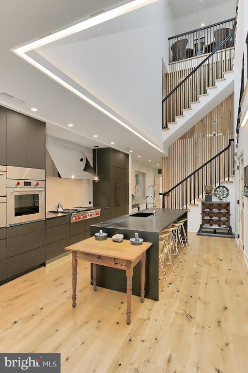 Modern kitchen with a large island and an open staircase with black railings.