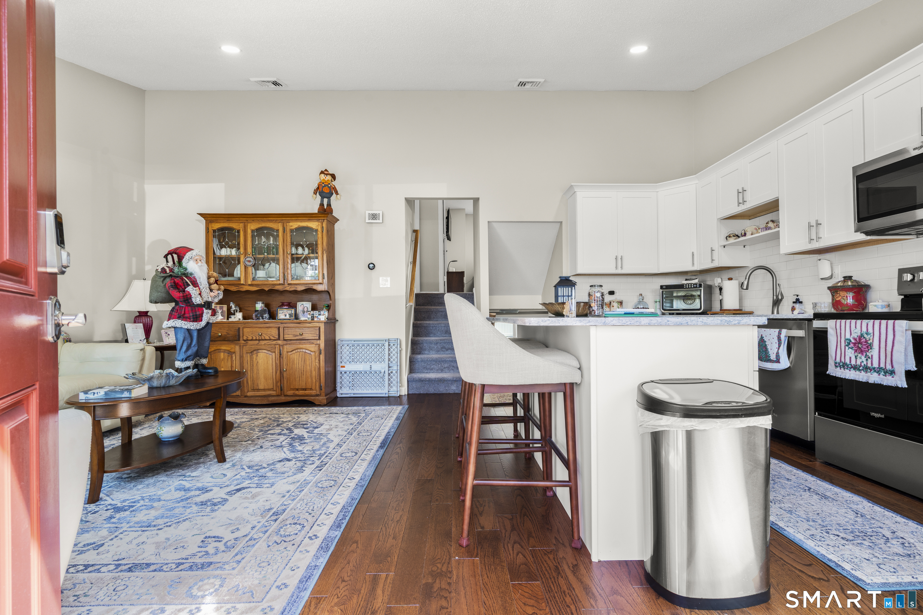 Open kitchen and living area with white cabinets, a breakfast island, and hardwood floors.