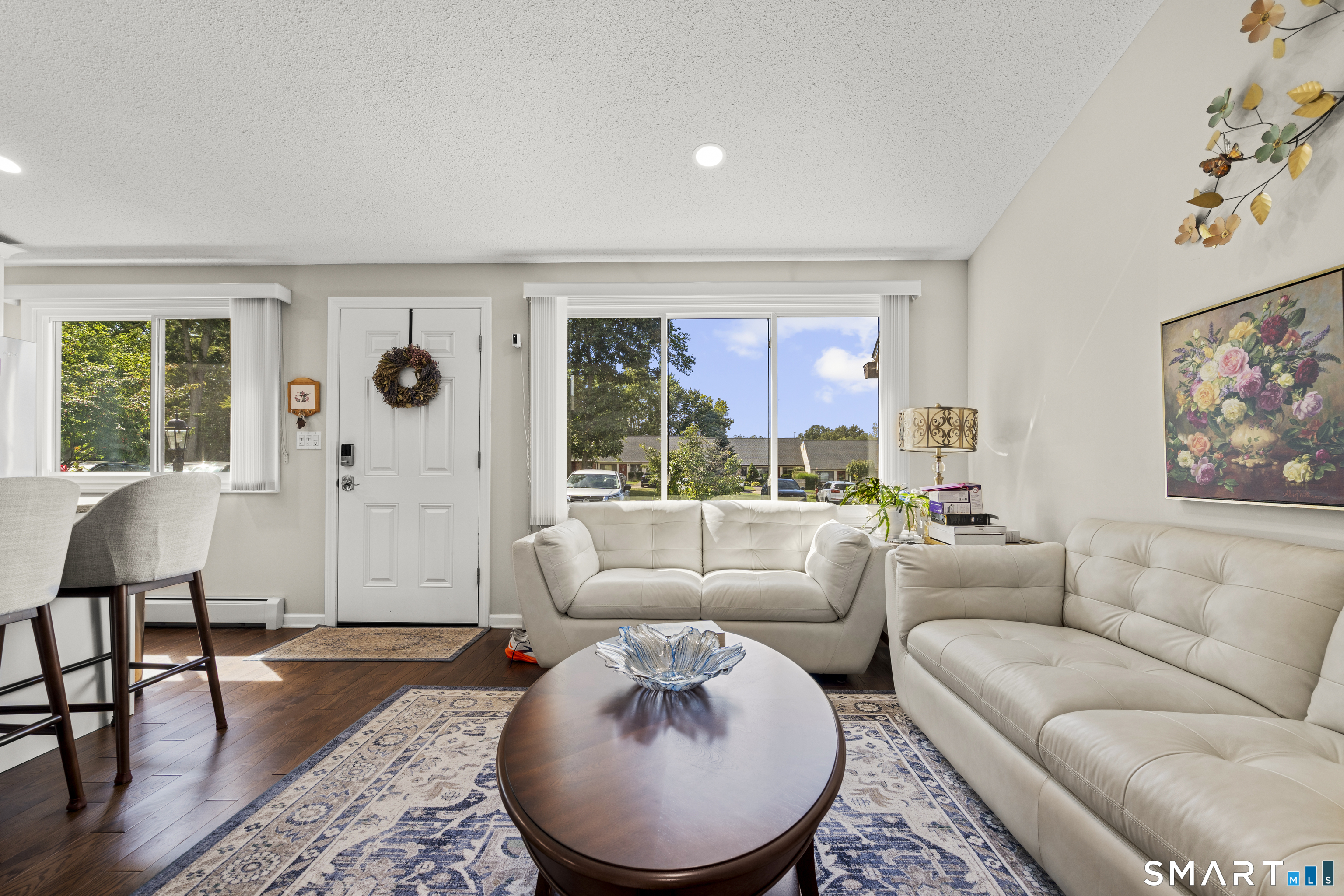 Living room with cream sofas, a wood coffee table, and large windows overlooking the complex.