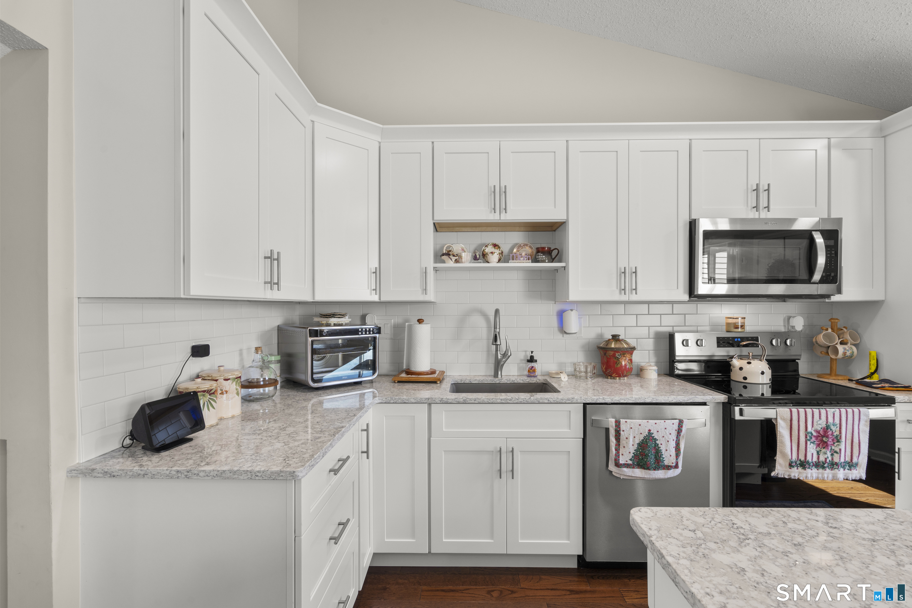 Kitchen with white cabinets, granite counters, stainless steel appliances, and a subway tile backsplash.