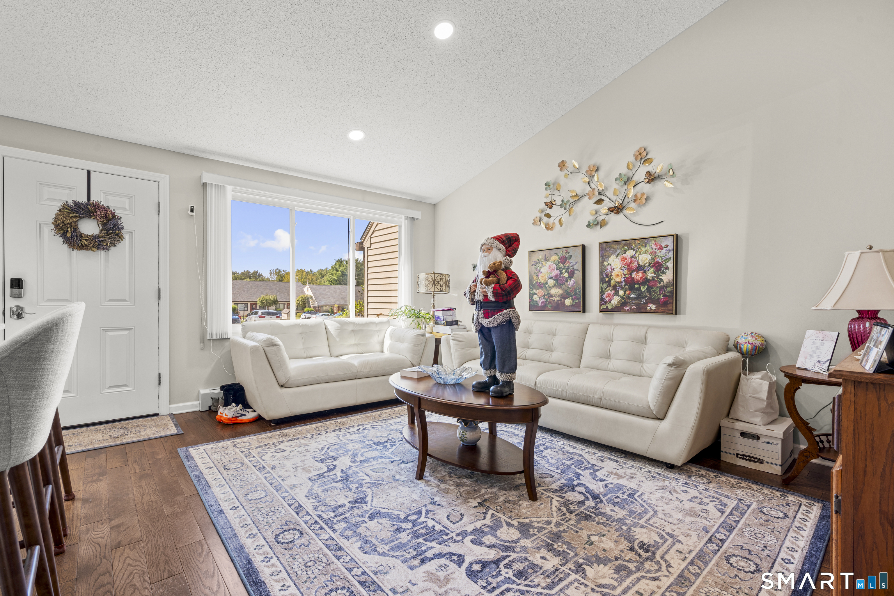 Living room with cream sofas, a patterned rug, and a Santa figure beside the window.