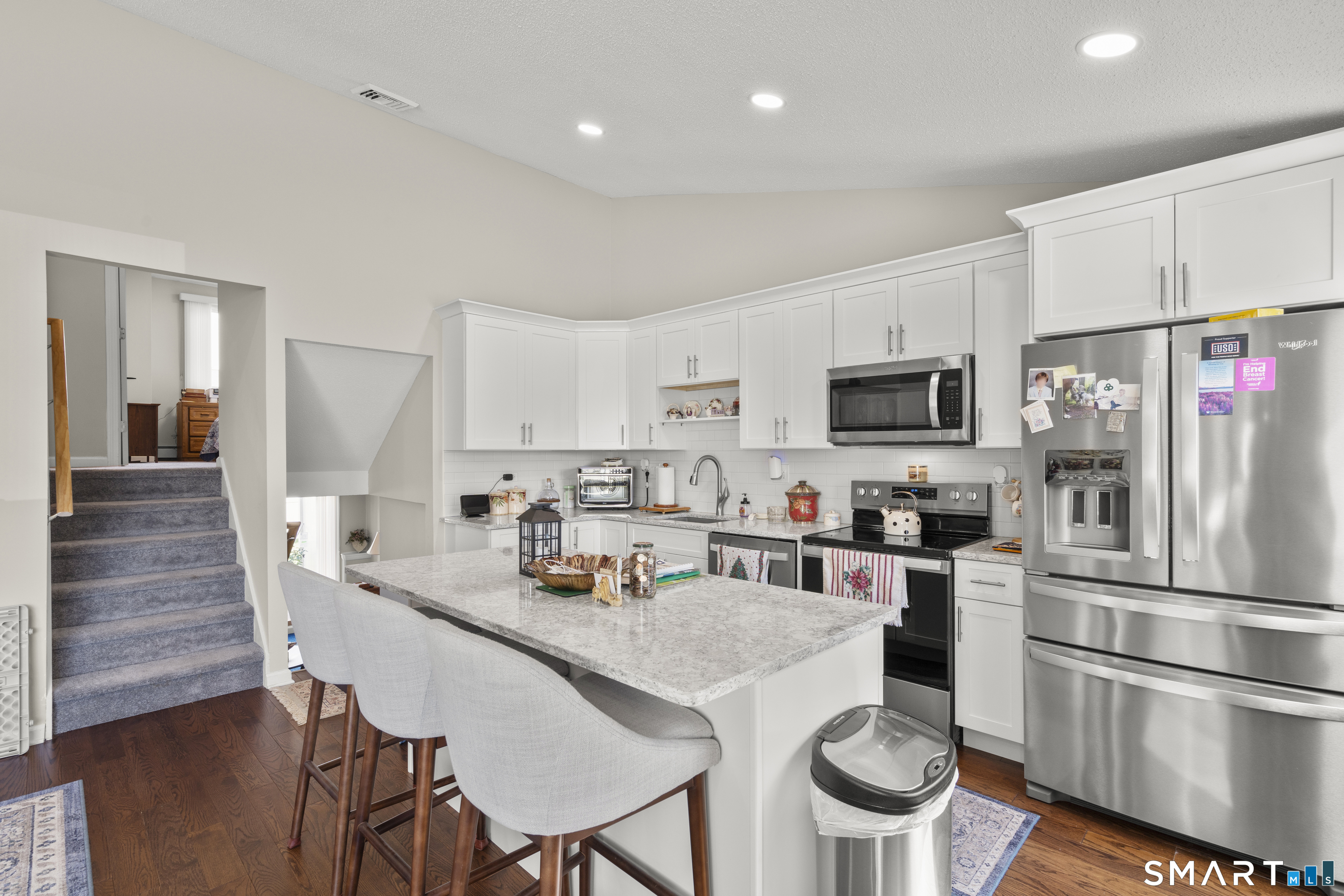 Kitchen with white cabinetry, a large marble-look island, and stainless steel appliances.