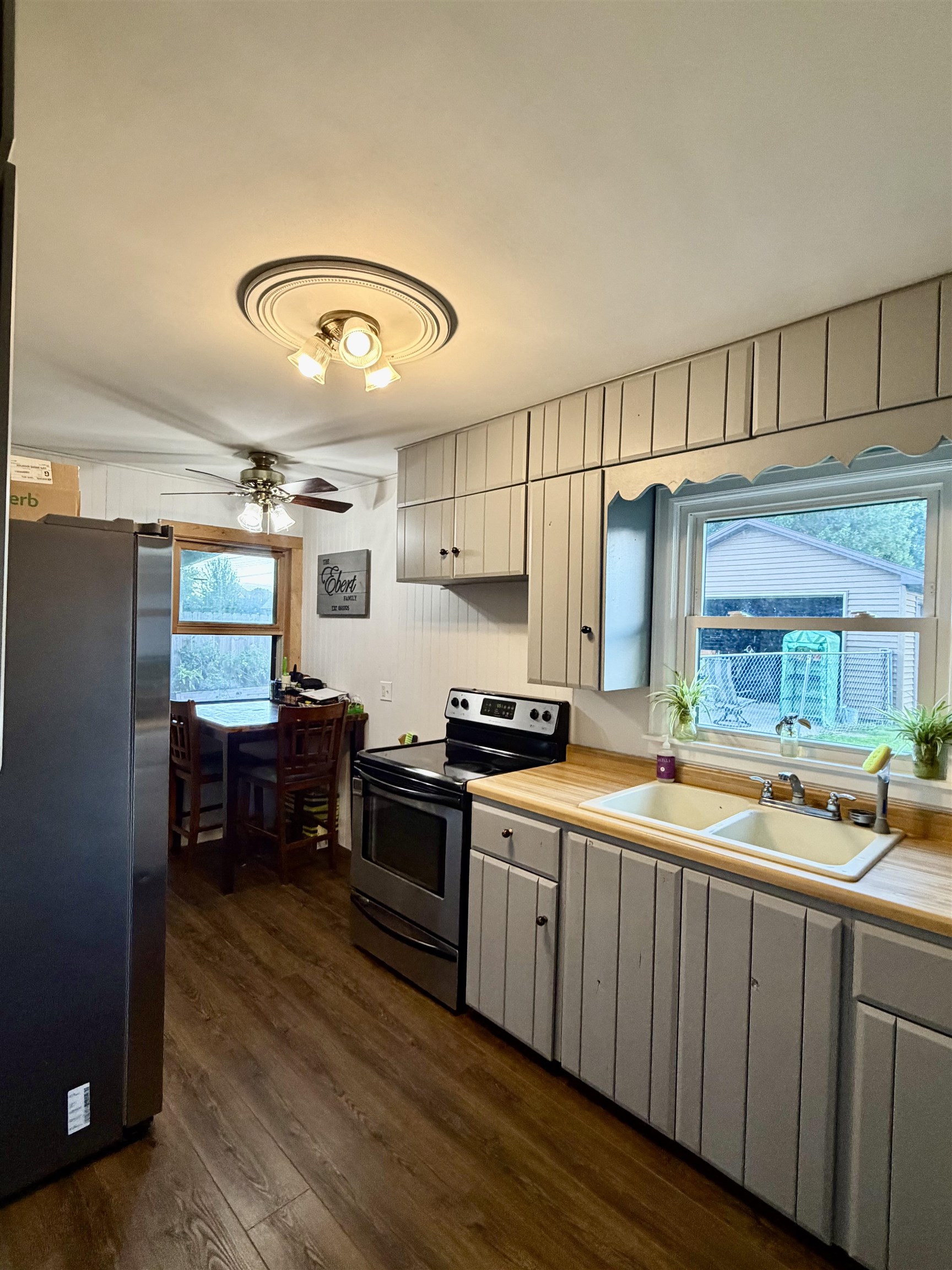 Kitchen with white paneled cabinets, wood counters, double sink, and a small dining table.