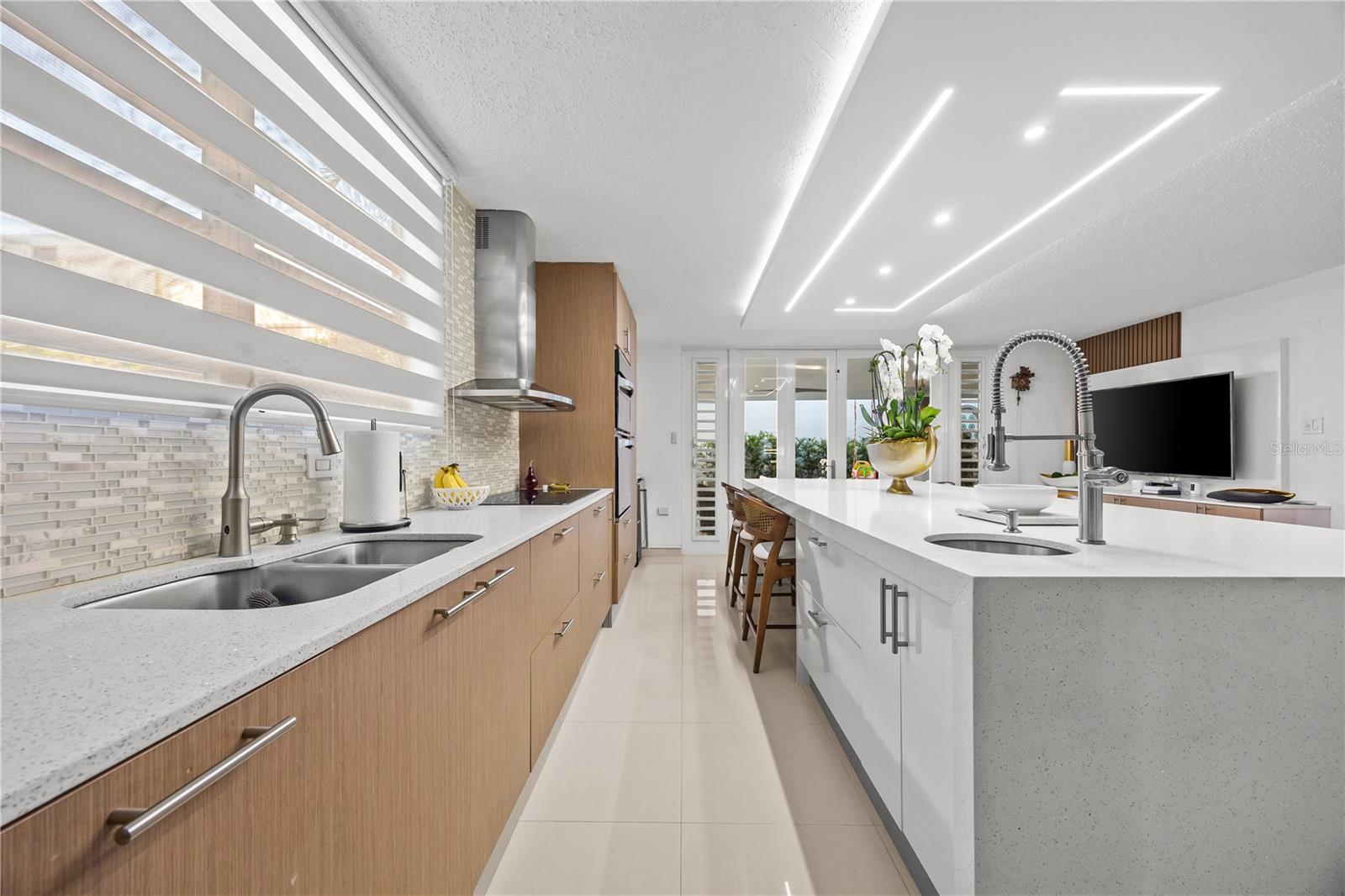 Modern kitchen with wood cabinetry, white counters, a large island, and geometric ceiling lights.