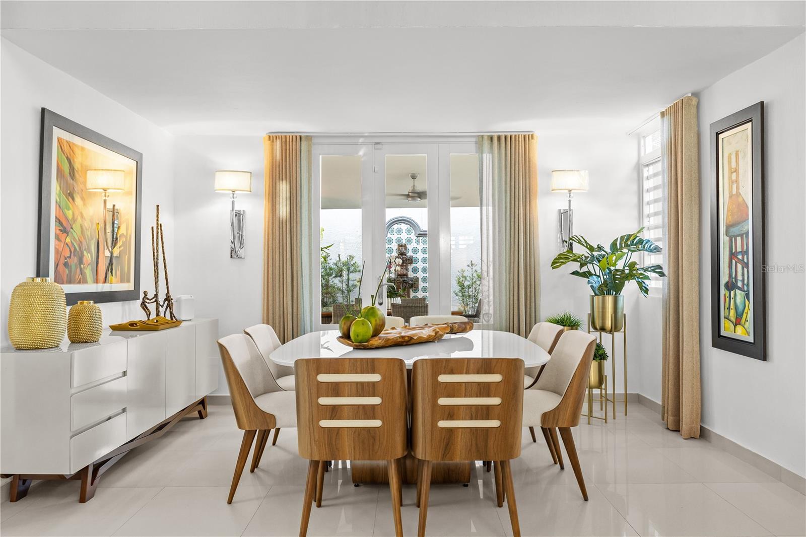 Dining room with a white table, wood chairs, and glass doors overlooking a patio and water.