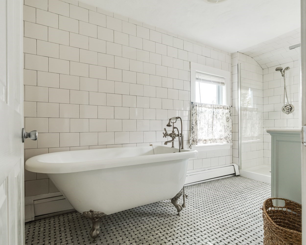 Bathroom with a white clawfoot tub, subway tile walls, and a black-and-white mosaic floor.