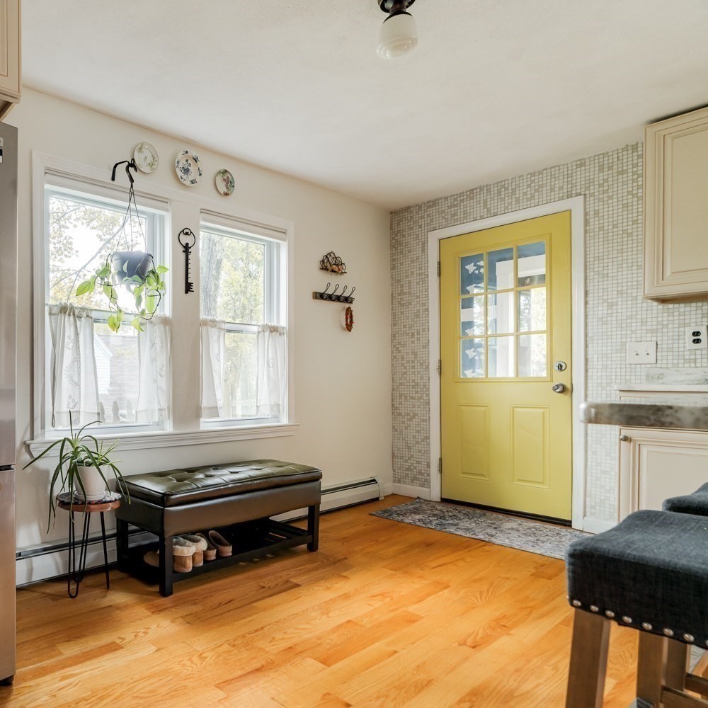 Kitchen entry with a yellow glass-paneled door, mosaic tile wall, and black storage bench.