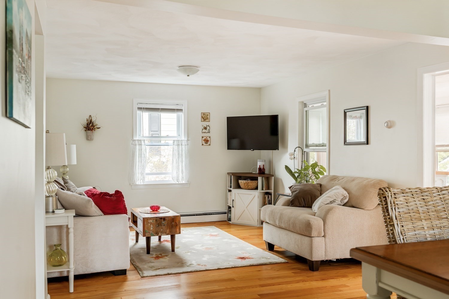 Furnished living room with hardwood floors, two sofas, and a wall-mounted television.