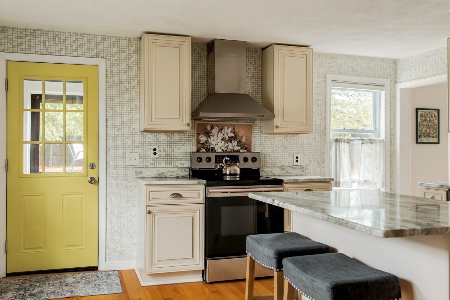 Kitchen with cream cabinets, marble counters, and a distinctive yellow door.