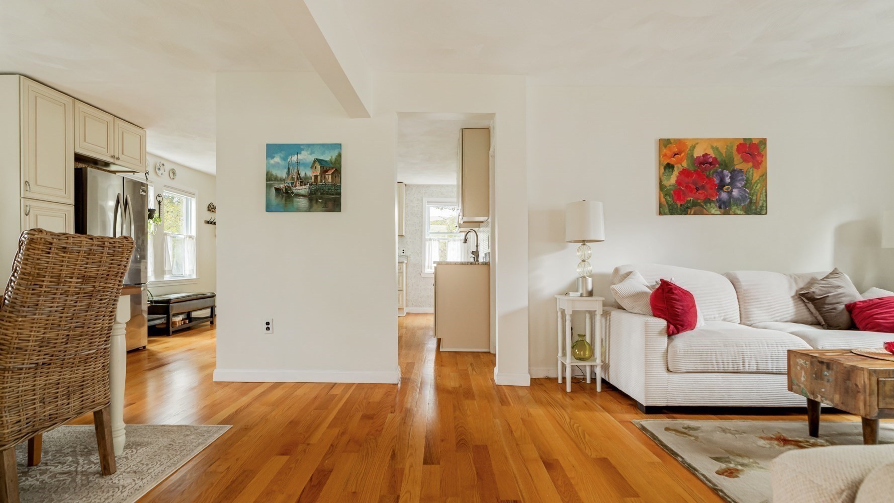 Open-plan living room and kitchen with hardwood floors and a white sectional sofa.