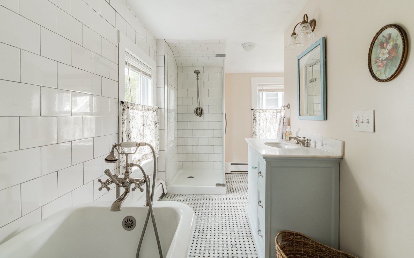Bright bathroom with a clawfoot-style tub, tiled walk-in shower, and pale blue vanity.