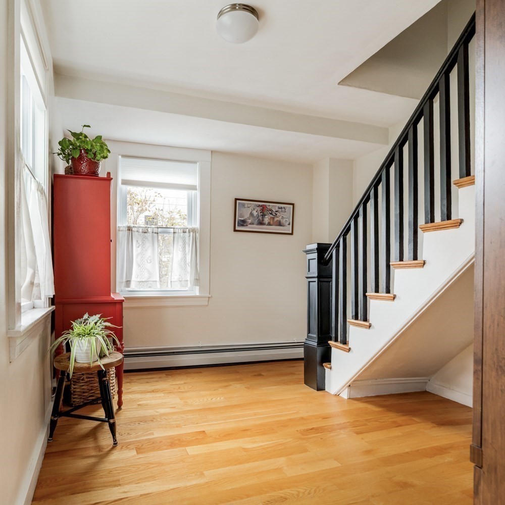 Entry hall with hardwood floors, a red cabinet, and a staircase with black balusters.