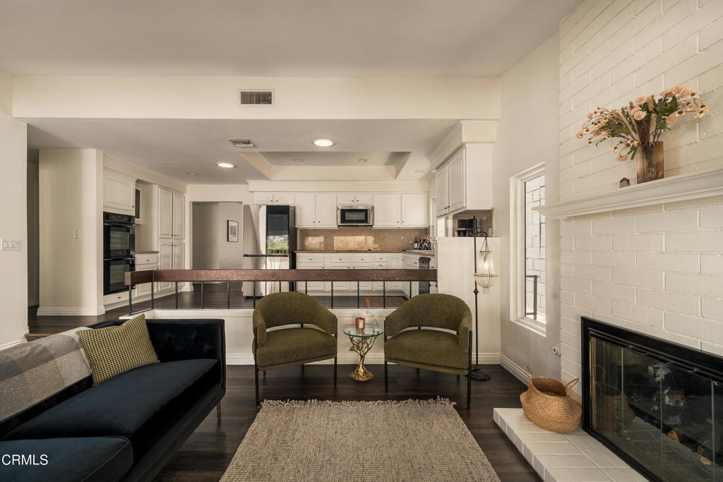 Open-plan living room and kitchen with a long bar counter and white brick fireplace.