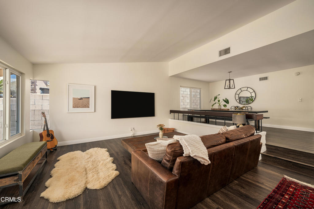 Living room with a brown leather sectional, wall-mounted TV, and adjoining dining area.
