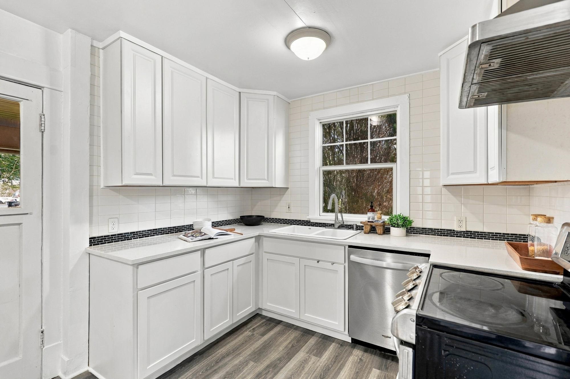 Kitchen with white cabinets, tiled backsplash, and a window over the sink.