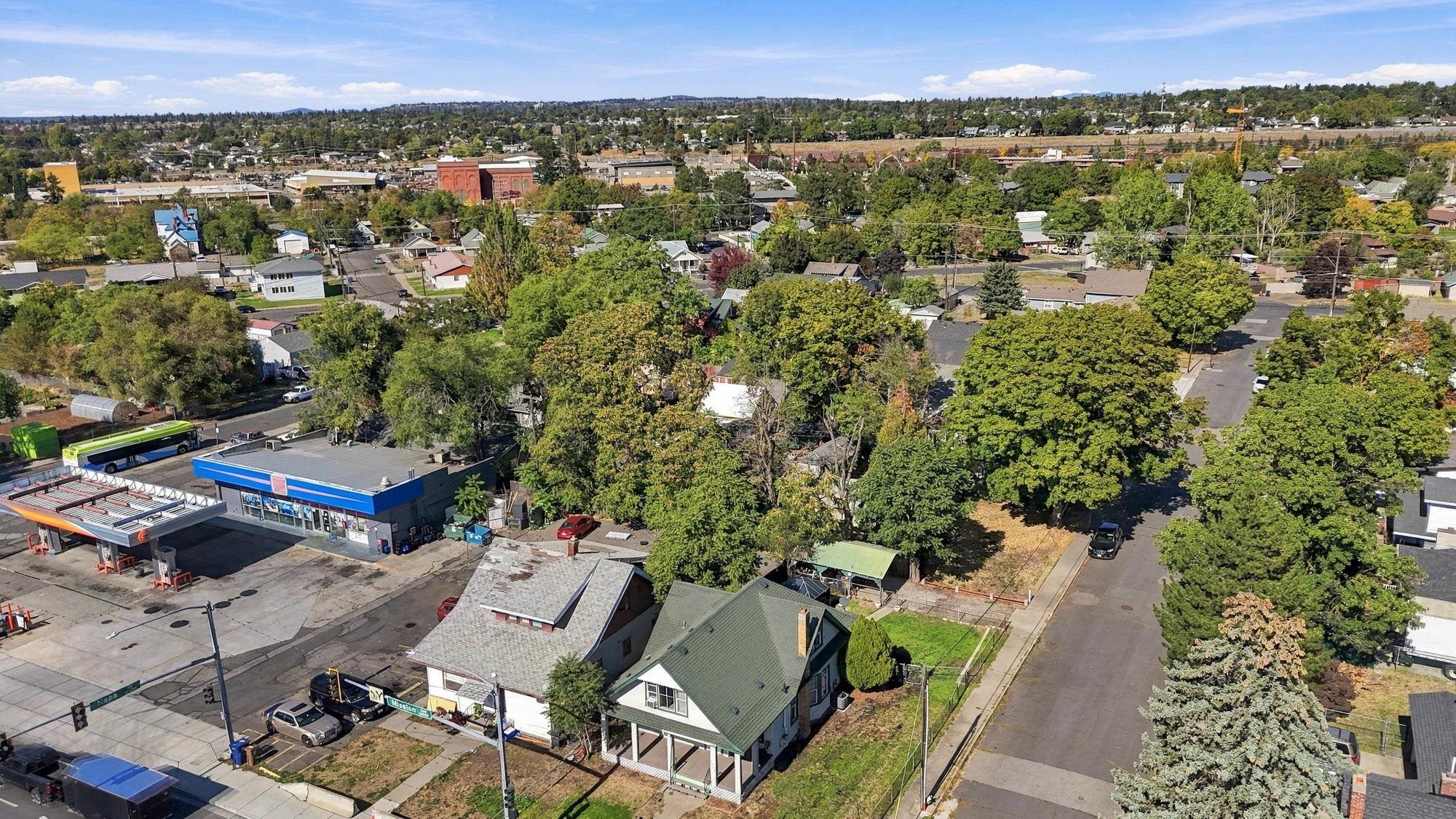 Aerial view of a Spokane neighborhood, with a green-roofed house among tree-lined streets and nearby businesses.
