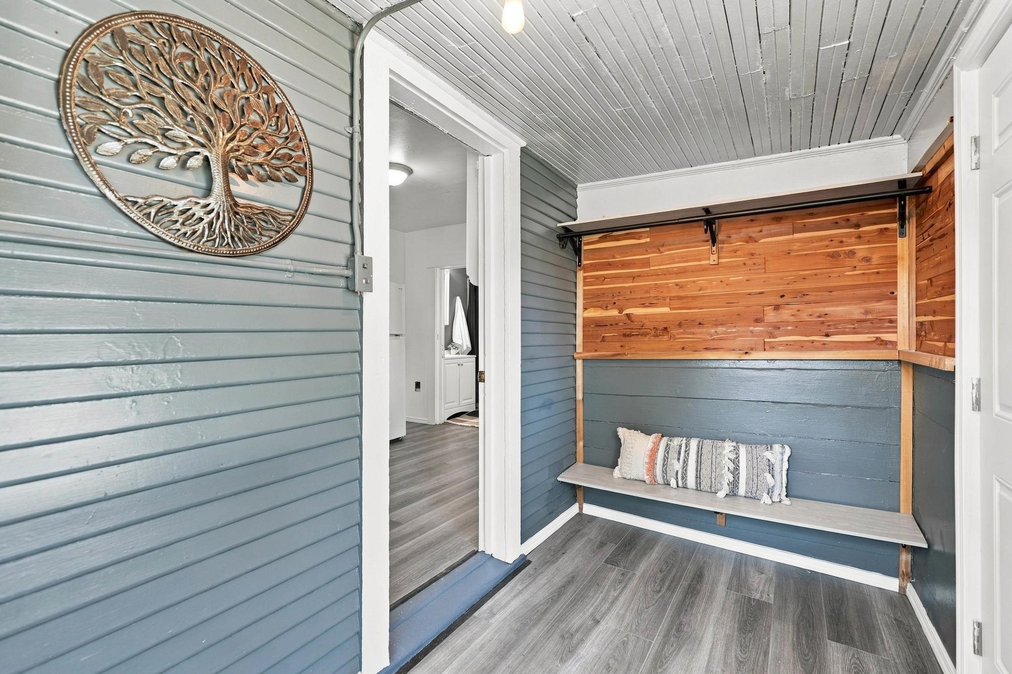 Entryway with a built-in bench, warm wood paneling, and blue-gray walls.