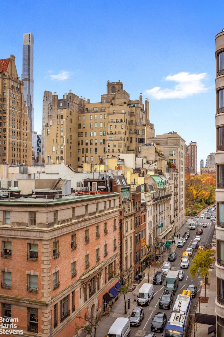 Manhattan street and rooftops viewed from above, with autumn trees and distant towers.