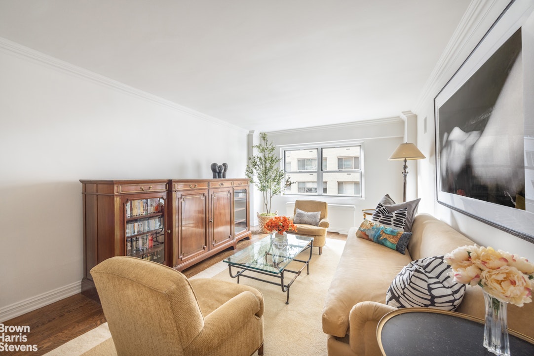 Living room with beige seating, a glass coffee table, and a dark wood cabinet.