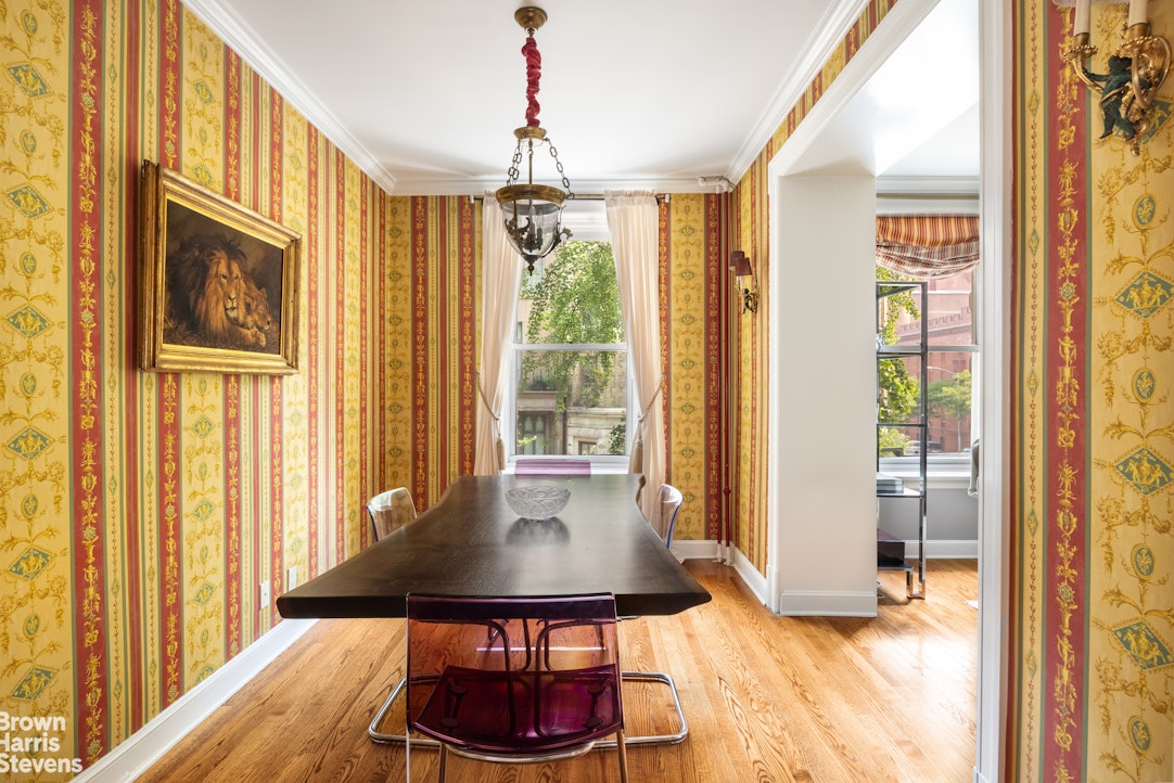 Dining room with ornate red-and-gold wallpaper, dark wood table, and hardwood floors.