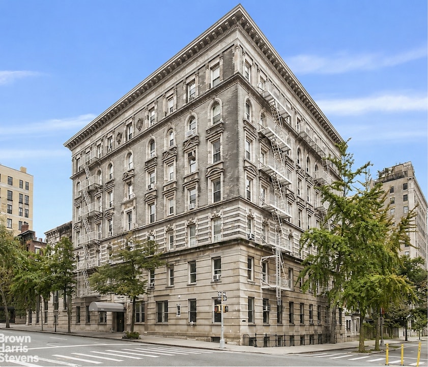 Corner apartment building with a stone facade, arched windows, and exterior fire escapes.