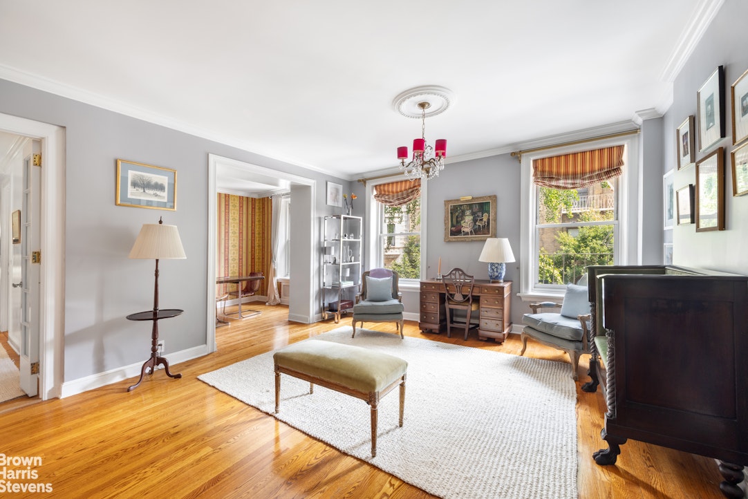 Living room with polished hardwood floors, tall windows, and a white area rug.
