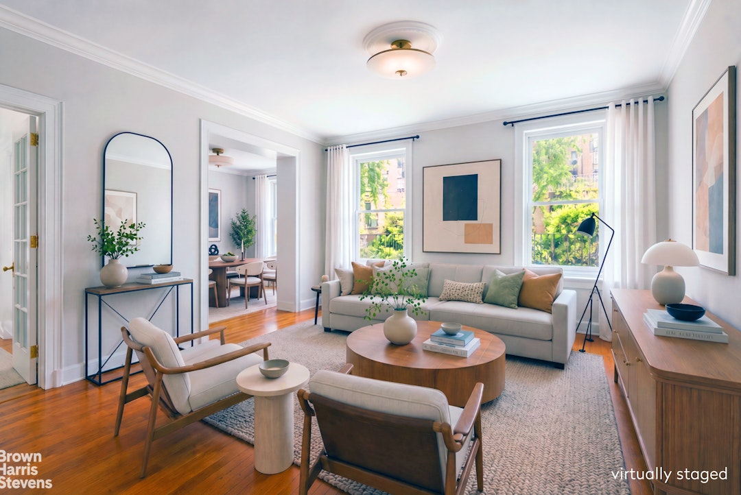 Virtually staged living room with a light sofa, wood coffee table, armchairs, and large windows.