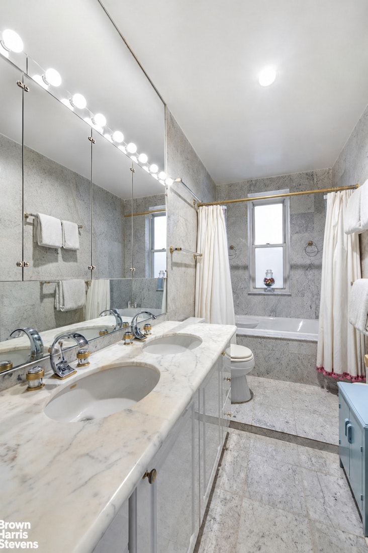 Marble bathroom with a double-sink vanity and curtained bathtub.