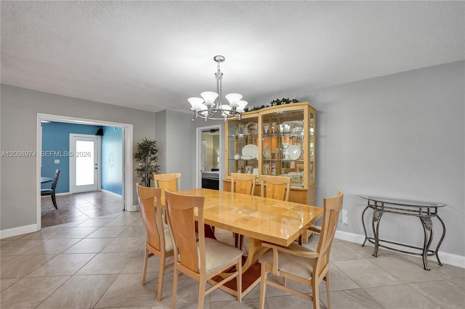 Dining room with a wooden table, glass-front china cabinet, and tiled floor.